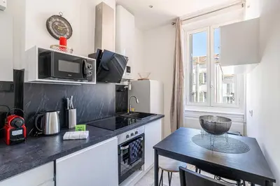 a small kitchen with a table and a microwave at Cozy One Bedroom apartment - heart of Cannes in Cannes