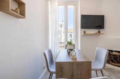 a living room with a table and chairs and a tv at Cozy One Bedroom apartment - heart of Cannes in Cannes