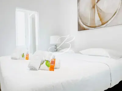 a white bed with towels and a mirror on it at Le Félix Faure - Palais Centre Cannes in Cannes
