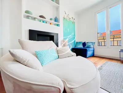 a white chair in a living room with a fireplace at Le Félix Faure - Palais Centre Cannes in Cannes