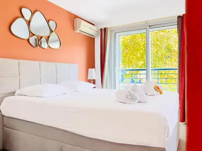 a bedroom with a large white bed with an orange wall at Le TerrAzur - Logement 4 personnes Cannes in Cannes