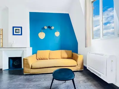 a living room with a yellow couch and a blue wall at Le BlueAzur - Proche Palais centre Cannes in Cannes
