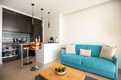 a living room with a blue couch and a table at Modern 1-bedroom apartment with sea view on La Croisette in Cannes