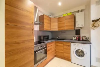 a kitchen with wooden cabinets and a washing machine at La Succulente - T1 bis climatisé proche plage in Cannes