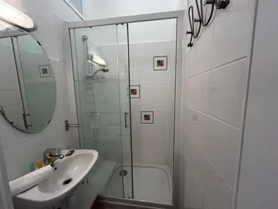 a white bathroom with a shower and a sink at A004 - Bright apt Rue d'Antibes at 300m from beach Croisette in Cannes