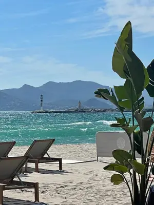 a beach with chairs and a lighthouse in the water at Valbois in Cannes
