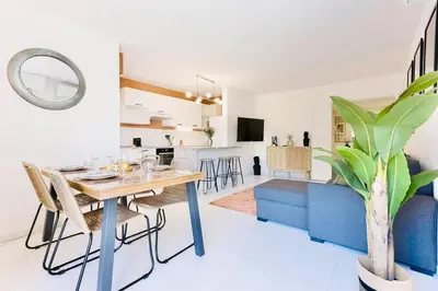 a dining room and living room with a table and a blue couch at Le Calmette - Logement Confort Centre Cannes in Cannes