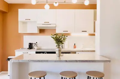 a kitchen with white cabinets and a counter with stools at Le Calmette - Logement Confort Centre Cannes in Cannes