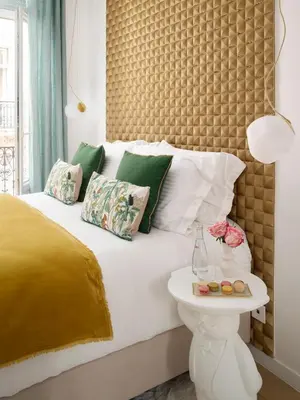 a bed with green and white pillows and a table at Le XV Cannes in Cannes