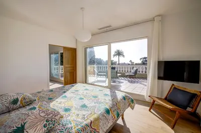a bedroom with a bed and a view of a patio at Villa rénovée- Vue mer- Centre de Cannes in Cannes