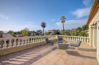 a balcony with chairs and a fence and palm trees at Villa rénovée- Vue mer- Centre de Cannes in Cannes