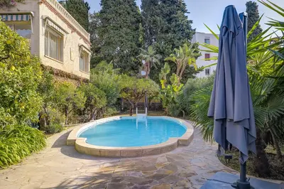 a swimming pool with an umbrella and a fountain at Villa rénovée- Vue mer- Centre de Cannes in Cannes