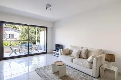 a white living room with a couch and a table at Charming apartment with balcony-pool - Cannes in Cannes
