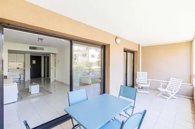 a patio with a blue table and chairs and a kitchen at Charming apartment with balcony-pool - Cannes in Cannes
