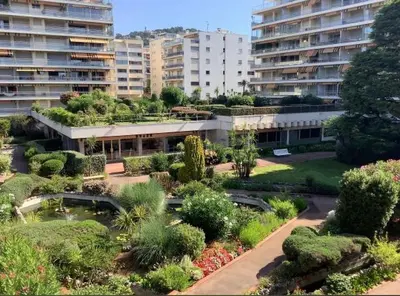 a building with a garden with bushes and trees at Парк Круазет , Апартаменты 3 комнаты , с террасой и паркингом , in Cannes