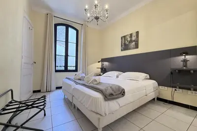 a bedroom with a large bed and a chandelier at Beautiful 2-bedroom apartment - near the Palais and the beaches in Cannes