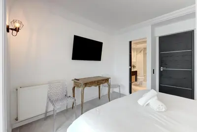 a white bedroom with a bed and a desk at Croisette sea view in Cannes