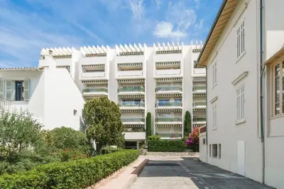 a white apartment building with a pathway in front of it at Studio Velasquez - Welkeys in Cannes
