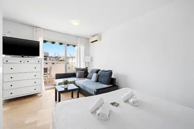 a white bedroom with a bed and a couch at Studio Velasquez - Welkeys in Cannes