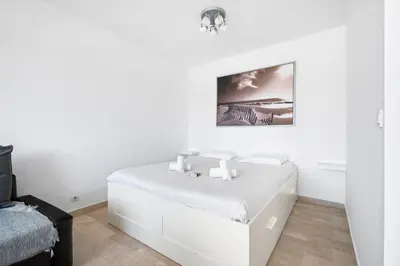 a white bedroom with a bed and a picture on the wall at Studio Velasquez - Welkeys in Cannes