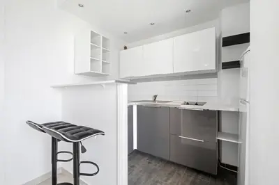 a kitchen with white cabinets and a stool at Studio Velasquez - Welkeys in Cannes