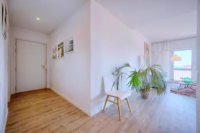 a white room with a chair and a plant at Downtown Cannes 2BR with AC & Terrace w Sea View - BENAKEY in Cannes