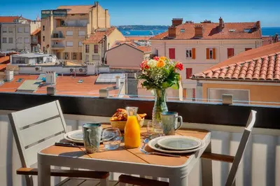 a table with a vase of flowers on a balcony at Downtown Cannes 2BR with AC & Terrace w Sea View - BENAKEY in Cannes