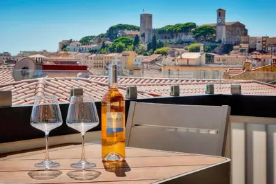 a bottle of wine and two glasses on a table at Downtown Cannes 2BR with AC & Terrace w Sea View - BENAKEY in Cannes