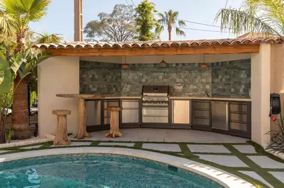 an outdoor kitchen with a swimming pool next to a house at Villa California Cannes Private Pool in Cannes