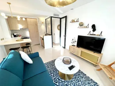 a living room with a blue couch and a kitchen at Palais Croisette Plage - 45 m2 Luxe - 2 Balcons in Cannes