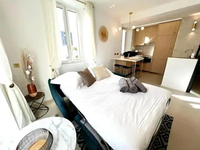 a room with a bed in a room with a kitchen at Palais Croisette Plage - 45 m2 Luxe - 2 Balcons in Cannes
