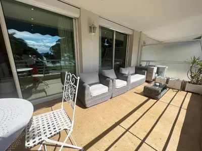 a patio with a couch and a chair on a balcony at Sea view Croisette in Cannes
