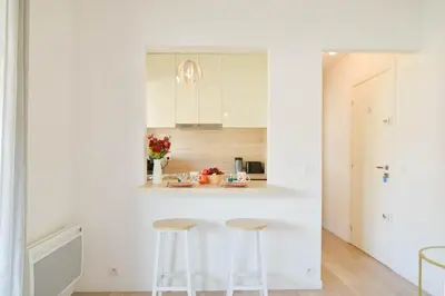 a kitchen with white cabinets and two stools at Palm Beach Studio with Terrace 150m from beaches in Cannes
