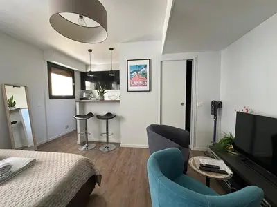 a living room with a table and chairs and a television at Un été à Cannes, Studio cosy à 10' de la Croisette in Cannes