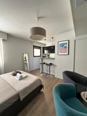 a bedroom with a bed and two chairs and a kitchen at Un été à Cannes, Studio cosy à 10' de la Croisette in Cannes