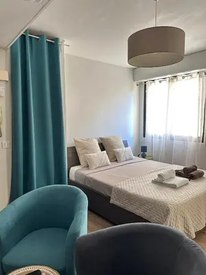 a bedroom with a bed and a blue chair at Un été à Cannes, Studio cosy à 10' de la Croisette in Cannes