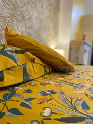 a bed with a yellow blanket with flowers on it at Appartement - Cannes proche Croisette avec jardin in Cannes