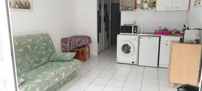 a living room with a couch and a washing machine at 2P en RDJ dans résidence avec piscine et tennis, proche Cannes et commodités in Le Cannet
