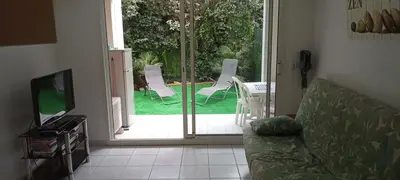 a living room with a couch and a sliding glass door at 2P en RDJ dans résidence avec piscine et tennis, proche Cannes et commodités in Le Cannet