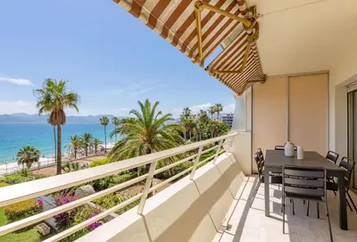 a balcony with a table and chairs overlooking the ocean at Georges III - Apartment with panoramic view of Cannes in Cannes