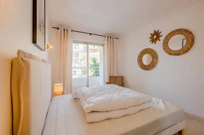 a white bedroom with a bed and a window at Georges III - Apartment with panoramic view of Cannes in Cannes