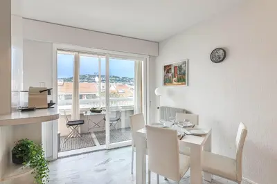 a white dining room with a table and a window at Appartement Cannes Centre Proche de la Croisette! in Cannes