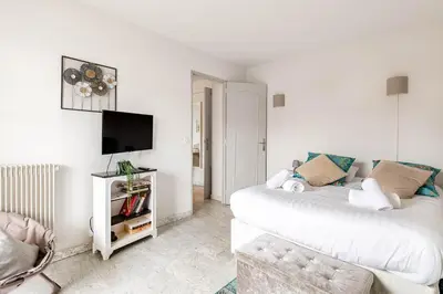 a white living room with a couch and a tv at Appartement Cannes Centre Proche de la Croisette! in Cannes