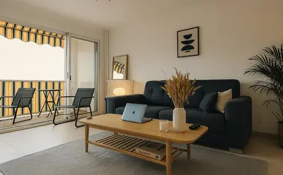 a living room with a couch and a table with a laptop at Charmant appartement avec terrasse in Le Cannet