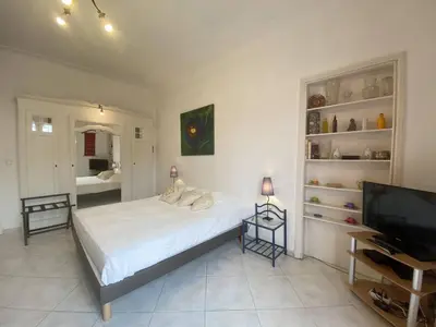 a bedroom with a bed and a flat screen tv at 242 Cannes La Croisette - PALAIS MIRAMAR - Studio au calme coté jardin in Cannes