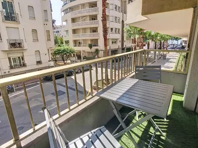 a picnic table and chairs on a balcony with a street at Beau 2 pièces proche Croisette avec parking 211 in Cannes