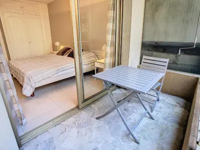a table and chair in a room with a bed at Beau 2 pièces proche Croisette avec parking 211 in Cannes