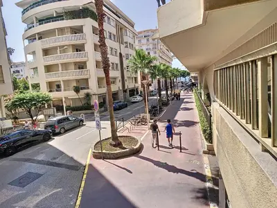 two people walking down a sidewalk next to a street at Beau 2 pièces proche Croisette avec parking 211 in Cannes