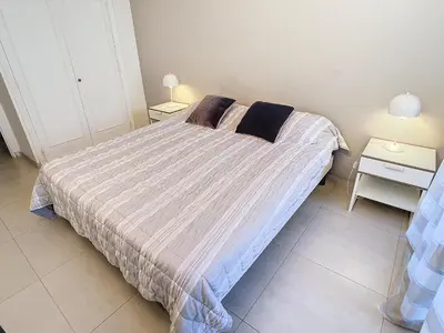 a bed in a room with two night stands and two lamps at Beau 2 pièces proche Croisette avec parking 211 in Cannes