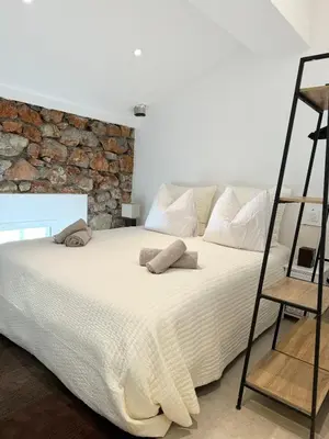 a bedroom with a large white bed with a stone wall at Charming appartement 3BR - 3BA - 3WC in Cannes